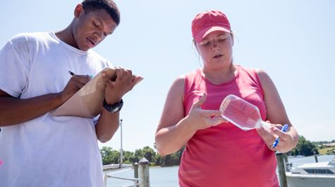 VIMS assistant professor Emily Rivest works with a local student to study experimental oysters deployed in the Rappahannock River as part of her Citizen Scientist Initiative. © Dominion Energy.