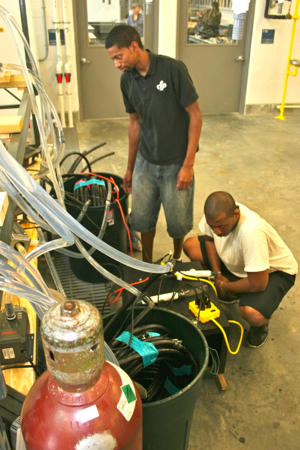 From L: Malik Breland and Cedrick Shamley Jr., of Hampton University prepare water lines for their study of the temperature preferences of Atlantic croaker. The pair are working with HU faculty member and VIMS alum Andrij Horodysky.
