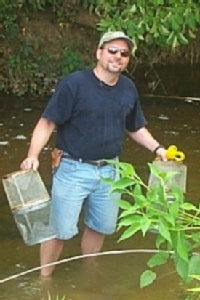 Mark LaGuardia collects samples from a freshwater stream for PBDE analysis.