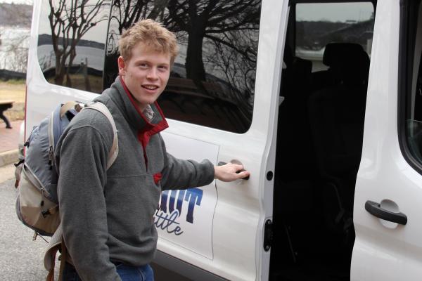 A W&M undergrad opens door to Batten School & VIMS shuttle.