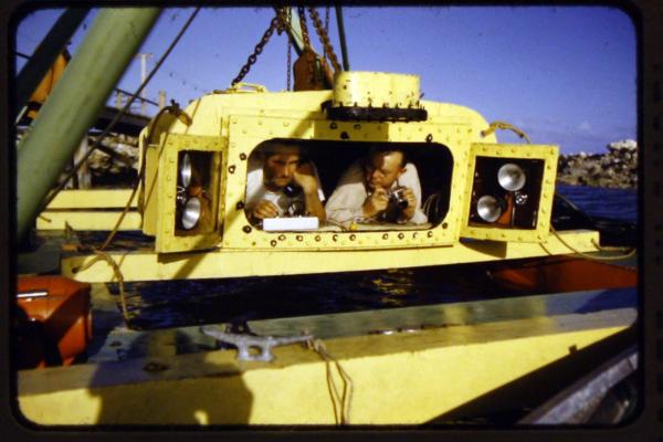Inventor Gilbert Klingel (Left) and photographer Willard Culver (Right) lie in the 3-000 pound Aquascope submersible, waiting to be lowered into the Chesapeake Bay on one of its 1953 voyages. Photo courtesy of the Mathews Museum.