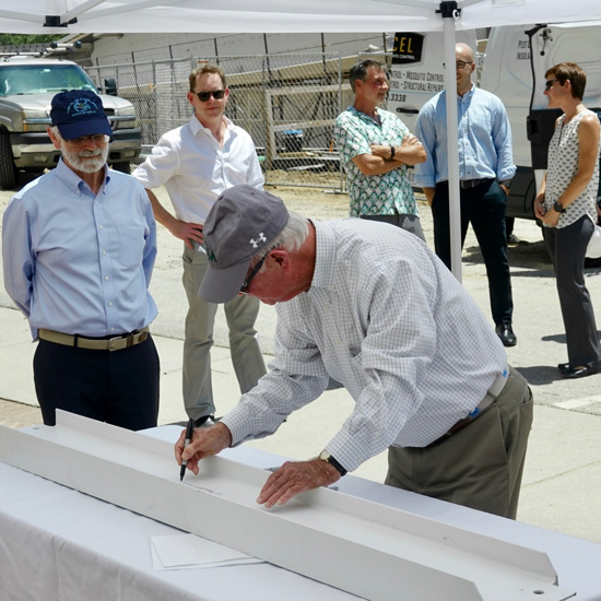 Marshall Acuff, Jr. joins others from VIMS, Kjellstrom + Lee Construction, and Quinn Evans architects to sign a roof-mounted I-beam as part of a June 30 "topping-off" ceremony for the Acuff Center for Aquaculture. © D. Malmquist/VIMS.