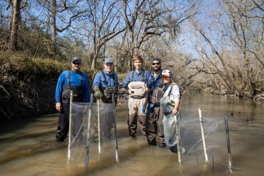 Researchers pose for group photo in river