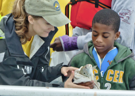 Marine recreation specialist Susanna Musick helps a youngster tag a fish during the Virginia Charter Boat Association's annual Youth Fishing Day. Photo by Janet Krenn.