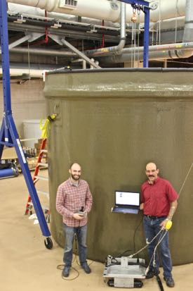 Dale McElhone and Paul Panetta with their Acoustic Slick Thickness ROV, in front of the 8,460-gallon tank they used for testing the vehicle inside VIMS’ Seawater Research Laboratory.