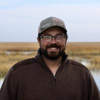 Headshot of William Sayers standing in front of some wetlands