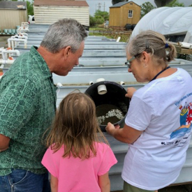 Karen Sisler speaks to two visitors on Marine Science Day.  She shows them oyster seed in the nursery and explains how to care for the young oysters.   