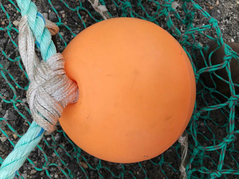 orange sphere-shaped float on trawl netting background